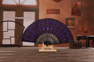 Close-up of a purple lace folding fan with sequins on a wooden stand in a vintage room