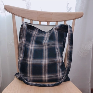 Vue détaillée d'un grand sac cabas en toile à carreaux bleu marine et marron sur une chaise