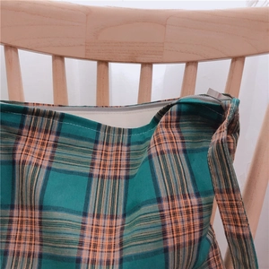 Détail du sac cabas à carreaux colorés avec fermeture éclair sur un dossier de chaise