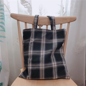 Gros plan d'un sac cabas en toile à carreaux rétro posé sur une chaise en bois