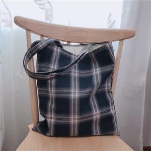 Sac fourre-tout en toile à carreaux bleu et gris suspendu à une chaise en bois