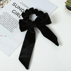 Detail view of premium black velvet bow scrunchie with long ribbons on a white table