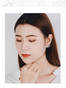 Close-up of silver leaf stud earrings with pavé diamonds on model ear