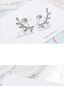 Macro shot of silver leaf earrings with cubic zirconia on white display card