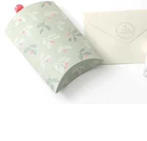 Detail of green leaf pattern pillow gift box with a beige Your Invited envelope