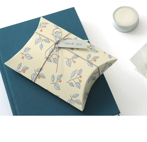 Detail view of pillow-shaped paper gift box with leaf patterns and Thank You tag