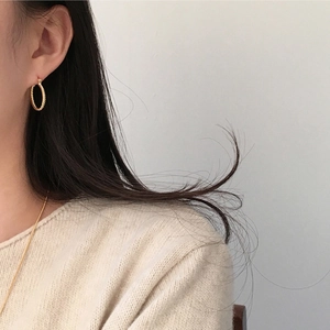 Close-up of elegant gold twisted hoop earrings worn by a model with a knit sweater