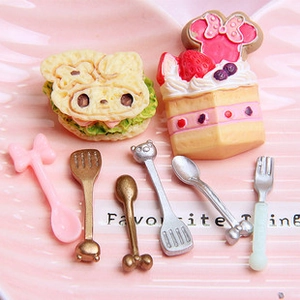 Macro detail of miniature dollhouse food set with cartoon plates and tiny cutlery