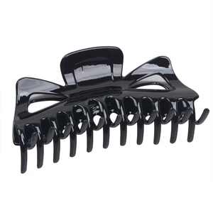 Macro view of a large glossy black hair claw clip with crossed teeth for thick hair