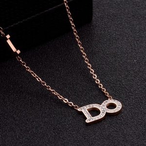 Macro shot of rose gold necklace with DO letter pendant and sparkling diamonds on black texture