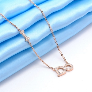 Close-up of rose gold I DO letter pendant with sparkling crystals on blue silk background