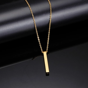 Macro shot of vertical gold bar pendant on fine chain over black reflective background