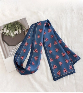 Detail of navy blue silk scarf with pink heart patterns on white wrinkled fabric