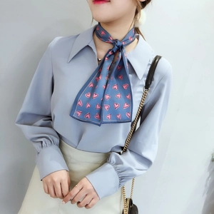Detail of blue skinny scarf with pink hearts tied in a bow around the neck