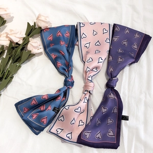 Chic heart pattern silk scarves in blue, pink, and purple, tied neatly on a white fabric