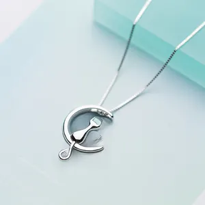 Macro shot of silver crescent moon and cat silhouette pendant with fine cross chain