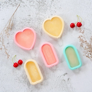 Flat lay of colorful silicone popsicle molds with heart and rectangle shapes on grey background