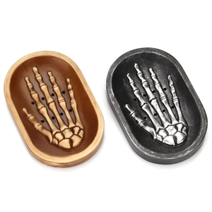 Detail of gothic skeleton hand soap dish with drainage holes in bronze and silver finishes