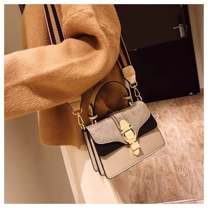 Close-up of color-block matte bag with golden metal lock and wide striped shoulder strap