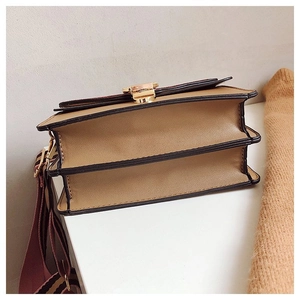 Detail view of the multi-layer accordion structure and gold metal buckle on tan shoulder bag