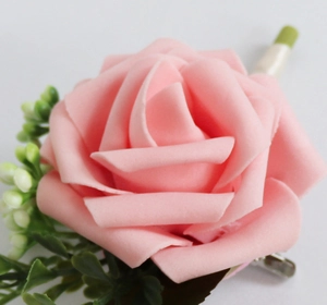 Gros plan d'une boutonnière rose en PE avec feuilles vertes et clip en métal sur blanc