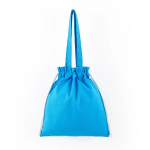 Detail of blue canvas drawstring tote bag with off-white cords on white background