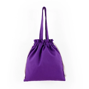 Close-up of purple canvas drawstring tote bag with long handles on white background