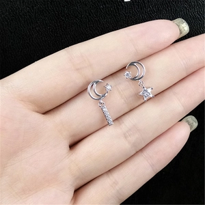 Macro shot of asymmetric silver earrings with moon and star pendants and white zircons