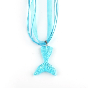 Detailed macro of a blue glitter mermaid tail pendant on a light blue ribbon necklace