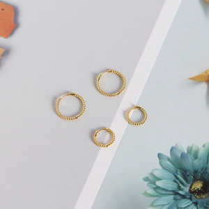 Detailed view of two pairs of gold twisted hoop earrings in large and small sizes