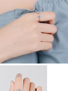 Detail of silver fishtail ring with blue enamel and small diamond on a finger