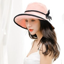 Detailed close-up of a pink summer sun hat featuring a black ribbon bow decoration