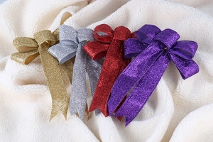 Macro detail of glitter Christmas bows in gold, silver, red, and purple on white plush
