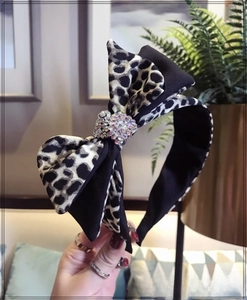 Detailed close-up of leopard print bow headband with sparkling rhinestone centerpiece