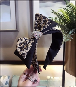 Detailed view of leopard print bow headband with sparkling rhinestone embellishments