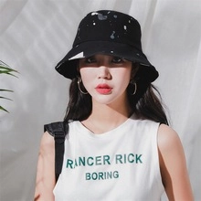 Detail shot of a black bucket hat with white splatter pattern on a bright white fabric