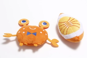 Detailed close-up of plush pet toy set with fine embroidery and soft orange fabric