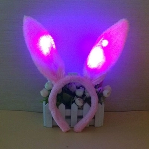 Detail of pink plush LED rabbit ears headband showing purple light on white fence