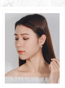 Close-up of golden bow-shaped stud earrings with sparkling crystals worn by a model