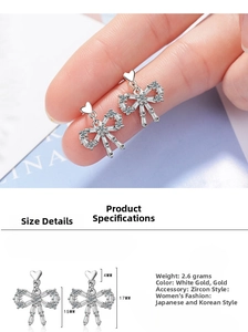 Detail of bow-shaped zircon earrings with heart studs in silver and gold finishes