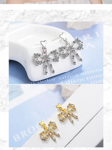 Detailed macro view of silver and gold bow earrings with shimmering zircon heart studs