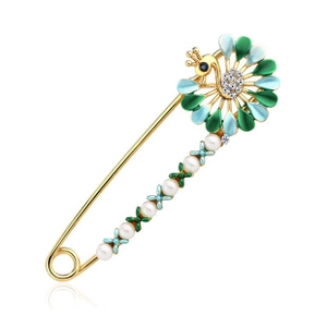 Close-up of golden peacock brooch with colorful enamel feathers and white pearls