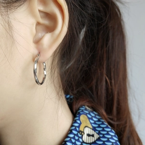 Close-up of twisted 925 sterling silver hoop earrings worn by a female model