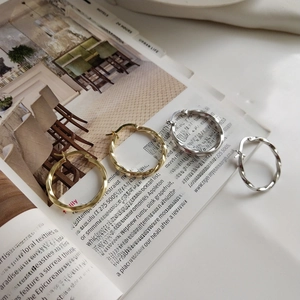 Macro detail of twisted rope hoop earrings in gold and silver finish on lifestyle book