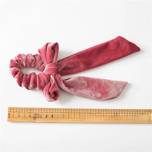 Pink velvet hair scrunchie with large bow and long streamers on a white background