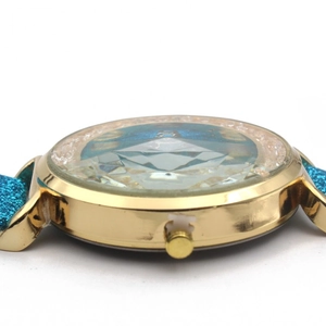 Close-up of faceted diamond-cut glass watch face with blue glitter strap detail