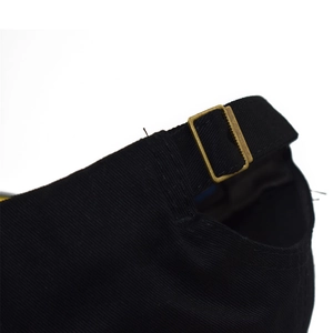 Close-up of adjustable bronze buckle on black cotton baseball cap with textured fabric