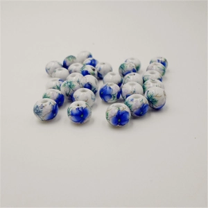 Macro shot of 10mm white ceramic beads with blue flower and green leaf patterns
