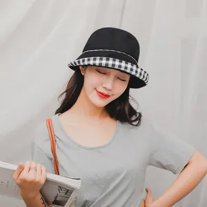 Detail of a black cotton bucket hat with a stylish black and white checkered brim detail