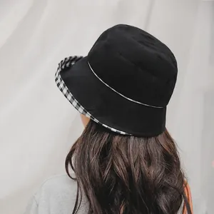 Detail of a black bucket hat featuring a stylish black and white plaid inner brim design